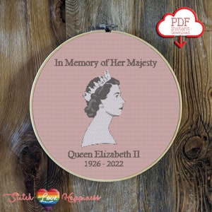 May include: A pink embroidery hoop with a black and white cross-stitch design of Queen Elizabeth II wearing a crown. The text "In Memory of Her Majesty Queen Elizabeth II 1926-2022" is stitched below the image.