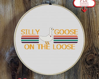 May include: Cross stitch pattern featuring a white goose with the text "Silly Goose On The Loose" in a retro style with orange, red, green, and brown stripes.