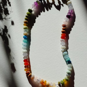 17 inches gemstone candy necklace strung on lilac silk. Agate, amazonite, apatite, citrine, fluorite, jade, jasper, labradorite, onyx, unakite, and quartz are used. There is a knot between each stone and finished with a 14k gold filled bold clasp