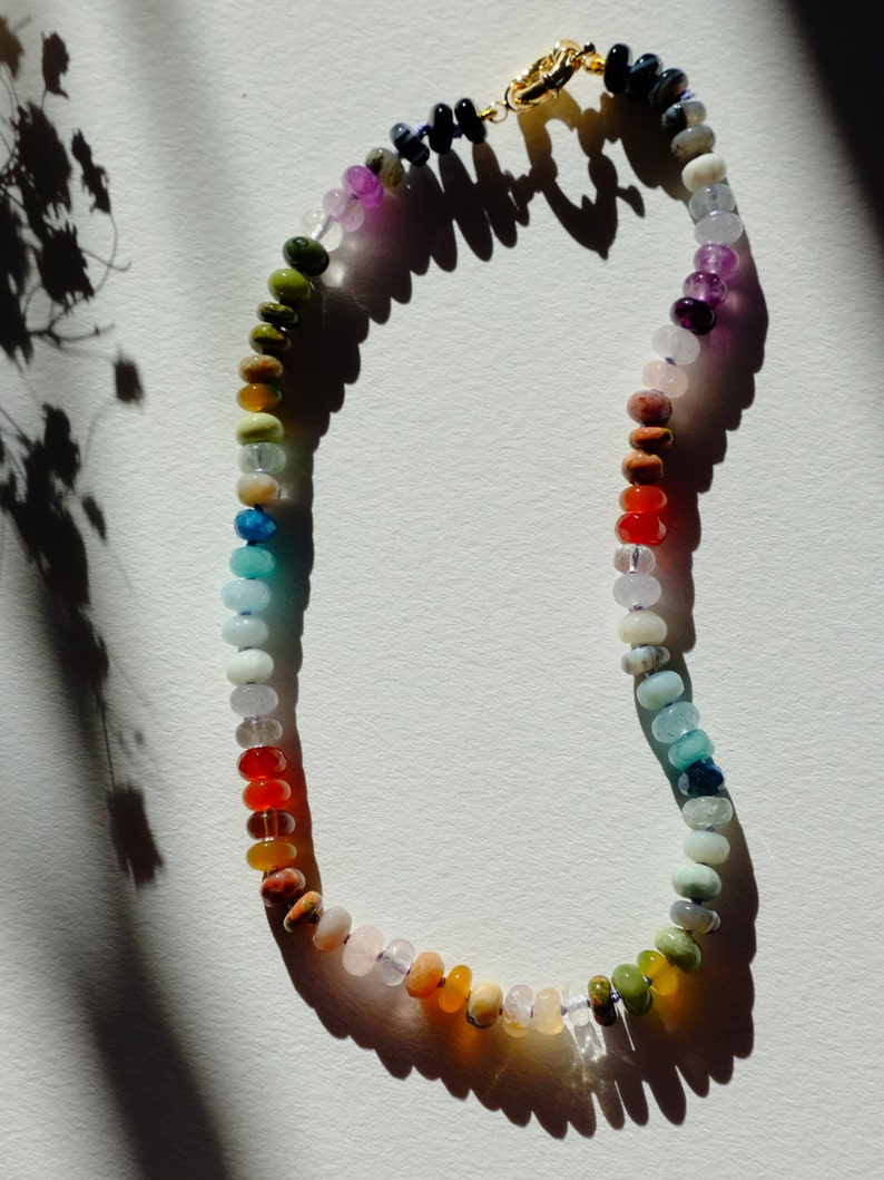 17 inches gemstone candy necklace strung on lilac silk. Agate, amazonite, apatite, citrine, fluorite, jade, jasper, labradorite, onyx, unakite, and quartz are used. There is a knot between each stone and finished with a 14k gold filled bold clasp