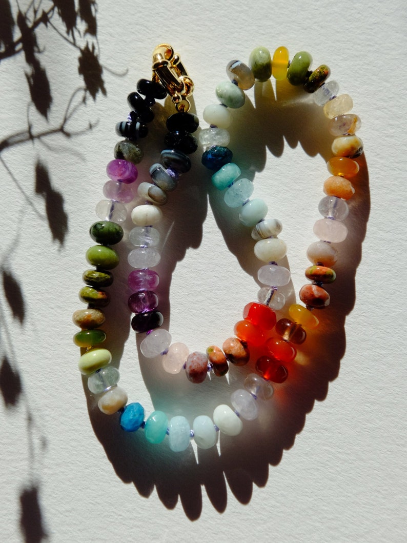 17 inches gemstone candy necklace strung on lilac silk. Agate, amazonite, apatite, citrine, fluorite, jade, jasper, labradorite, onyx, unakite, and quartz are used. There is a knot between each stone and finished with a 14k gold filled bold clasp