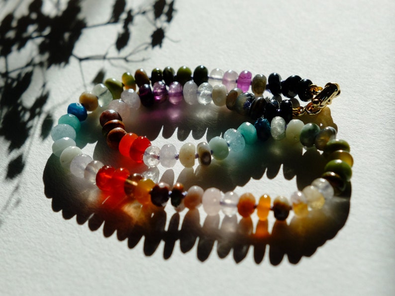 17 inches gemstone candy necklace strung on lilac silk. Agate, amazonite, apatite, citrine, fluorite, jade, jasper, labradorite, onyx, unakite, and quartz are used. There is a knot between each stone and finished with a 14k gold filled bold clasp