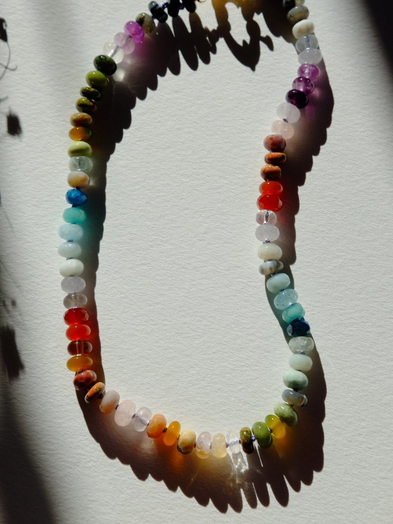 17 inches gemstone candy necklace strung on lilac silk. Agate, amazonite, apatite, citrine, fluorite, jade, jasper, labradorite, onyx, unakite, and quartz are used. There is a knot between each stone and finished with a 14k gold filled bold clasp