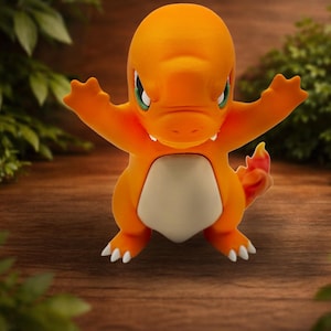 May include: Orange Charmander figurine with outstretched arms, white belly, and a flame-tipped tail. The figure has green eyes and white claws. The background features greenery and a wooden surface.