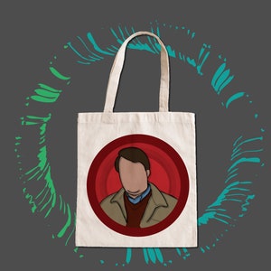 Peut inclure: Un sac fourre-tout en toile de couleur crème avec une illustration de dessin animé d'une personne dans un cercle rouge. La personne porte une veste beige, un pull rouge et une chemise bleue. Le fond est gris avec des coups de pinceau verts et turquoise.