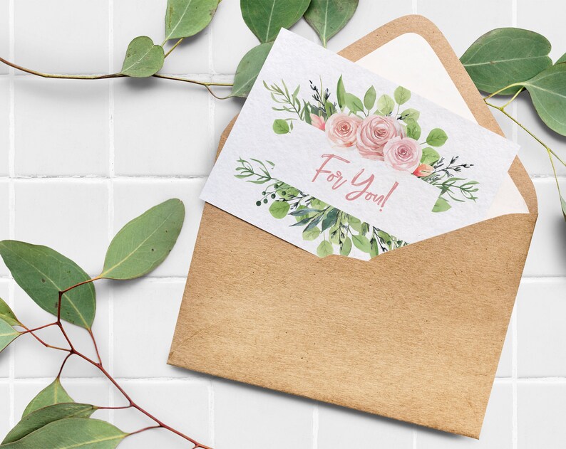 May include: A kraft paper envelope with a white card inside. The card has a watercolor illustration of pink roses and green leaves. The text "For You!" is written in pink on the card.