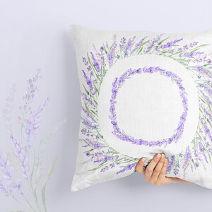 May include: A white pillow with a lavender wreath design. The wreath is made of watercolor purple and green lavender flowers.