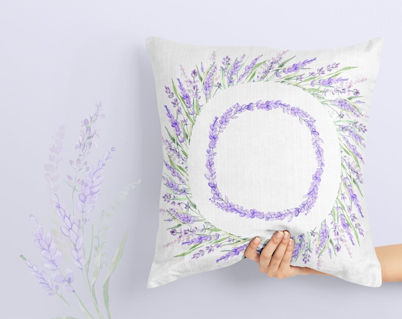 May include: A white pillow with a lavender wreath design. The wreath is made of watercolor purple and green lavender flowers.
