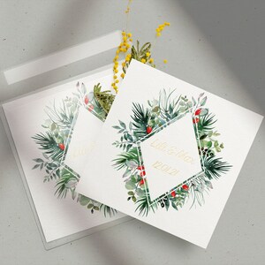Op de afbeelding: Twee witte kaarten met een groen en rood bloemenontwerp en een gouden geometrisch frame. De tekst "Lori & Max 12.01.2021" staat op een kaart binnen het frame.