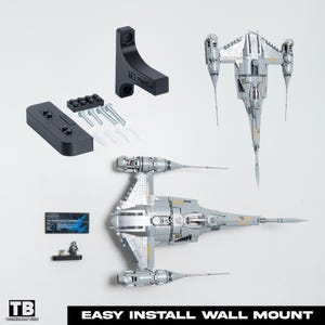 Op de afbeelding: Een zwarte wandmontageset voor een model ruimteschip, met montagemateriaal en een klein beeldje. Het ruimteschip is zilver en grijs. De tekst "EASY INSTALL WALL MOUNT" staat onderaan.