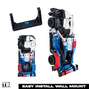 May include: A black wall mount and a blue, white, and red model car. The wall mount has the text "TB 42226V". The model car is in the process of being assembled. The bottom of the image has the text "EASY INSTALL WALL MOUNT".