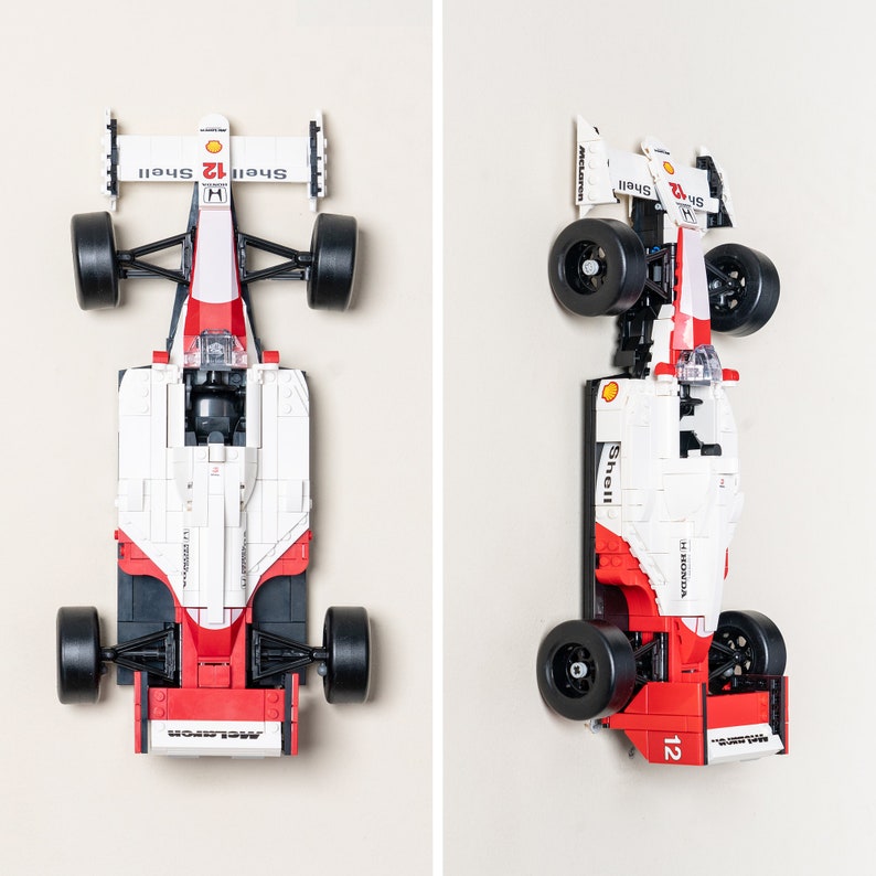 May include: A red and white Lego model of a Formula 1 race car with the words "Shell" and "Honda" on the side. The car is on a white background.