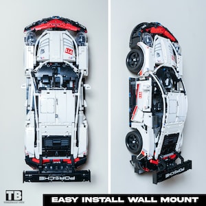以下が含まれることがあります： 赤色のアクセントが付いた白と黒のレゴポルシェ911 GT3 RSモデルカー。車は黒い壁掛けで壁に取り付けられています。車の真下に「EASY INSTALL WALL MOUNT」というテキストが印刷されています。