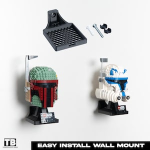 Könnte beinhalten: Ein schwarzes Wandhalterungs-Kit mit zwei Star Wars Lego-Helmen: Boba Fett und ein Clone Trooper. Die Helme sind an einer weißen Wand montiert. Der Text "EASY INSTALL WALL MOUNT" befindet sich am unteren Rand des Bildes.