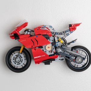May include: A red and black Ducati Corse motorcycle model kit. The motorcycle features a detailed engine and a chain drive. The model is made from plastic and metal.