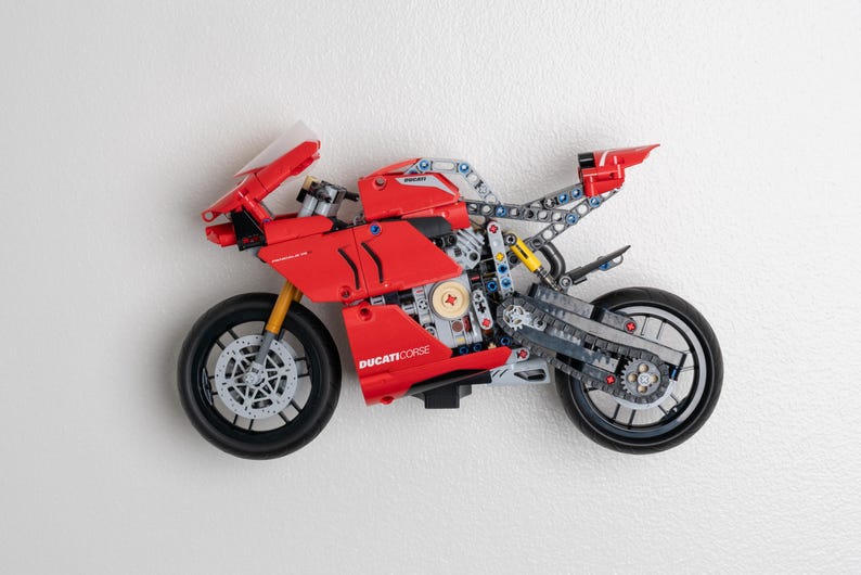 May include: A red and black Ducati Corse motorcycle model kit. The motorcycle features a detailed engine and a chain drive. The model is made from plastic and metal.