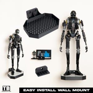 Puede incluir: Soporte de pared negro para una figura LEGO K-2SO, con el texto "EASY INSTALL WALL MOUNT". El soporte se muestra con la figura LEGO y una pequeña estantería de exhibición. La figura es negra y gris con detalles amarillos.
