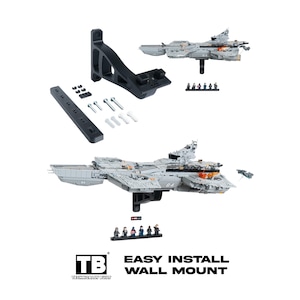 May include: A black plastic wall mount bracket for a gray building block aircraft carrier model. Includes a long mounting bar, screws, wall anchors, and a small display stand with six miniature figures. Text reads: TB TECHNICALLY BUILT EASY INSTALL WALL MOUNT.