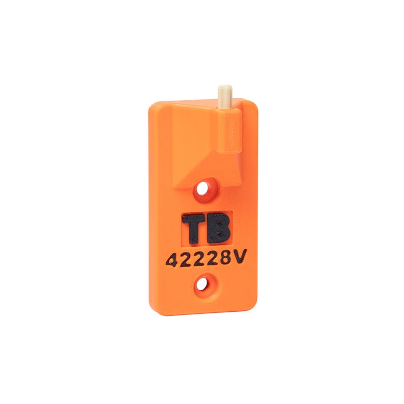 May include: A rectangular orange plastic component featuring a small beige cylindrical protrusion at the top, two circular mounting holes, and the black embossed text TB 42228V centered on the front surface of the device.