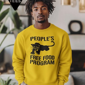 以下が含まれることがあります： 黒い文字で「PEOPLE'S FREE FOOD PROGRAM」と書かれたマスタードイエローのスウェットシャツ。黒いパンサーのグラフィックが特徴です。Day Party Teesのロゴが左上にあります。