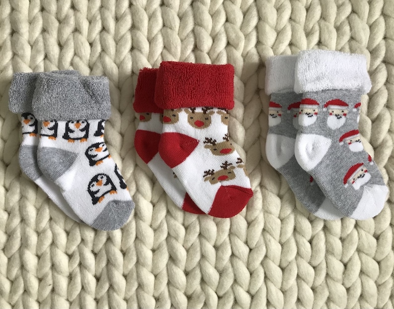 Op de afbeelding: Drie paar kerstsokken voor baby's. E&eacute;n paar heeft pingu&iuml;ns, een ander paar heeft rendieren en het laatste paar heeft kerstmannen.