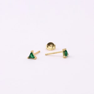 May include: A pair of gold triangle earrings with green gemstones.