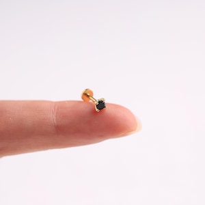 May include: A gold nose stud with a small black gemstone.