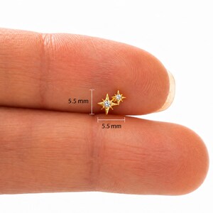 May include: A gold-toned stud earring featuring two connected star-shaped charms, each set with a small clear stone. The earring measures 5.5 mm in height and 5.5 mm in width as indicated by the measurement lines visible on the product.