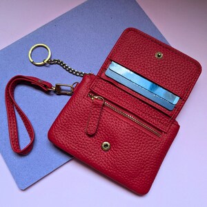 Open close up of the red wallet with a zipper section and key ring.