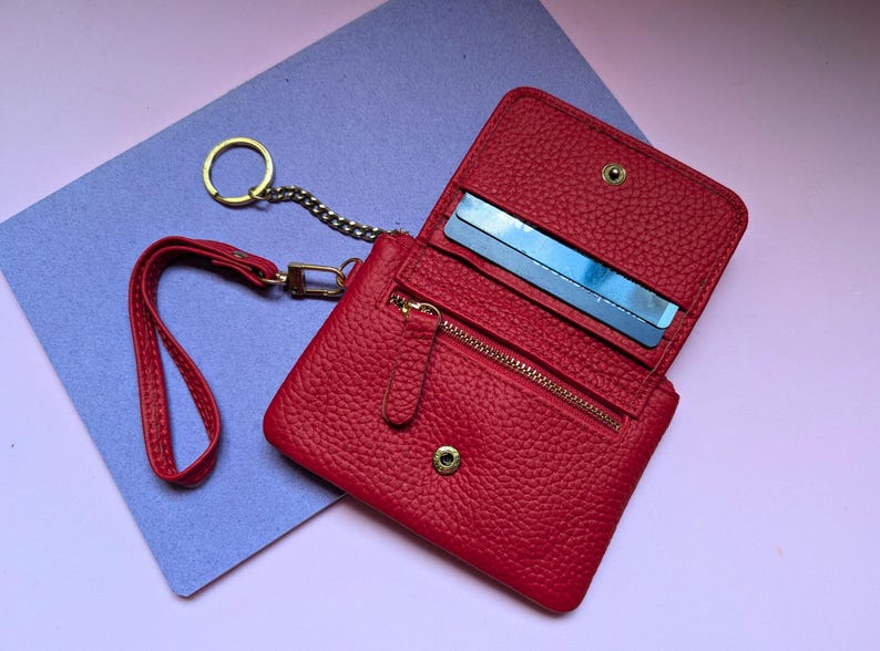 Open close up of the red wallet with a zipper section and key ring.
