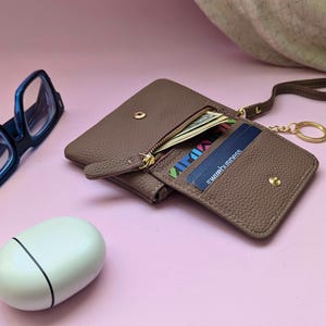 Mauve card holder with keyring, zipper purse and internal pocket in an opendisplay.