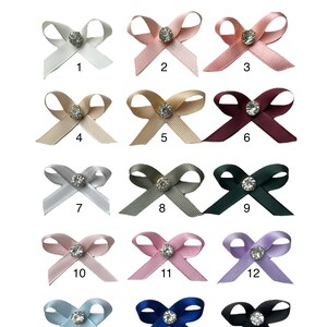 K&ouml;nnte beinhalten: Eine Sammlung von f&uuml;nfzehn Satin-Schleifen in verschiedenen Farben, jede mit einem funkelnden Strassstein in der Mitte. Die Schleifen sind von 1 bis 15 nummeriert, mit Farben wie Wei&szlig;, Rosa, Gold, Burgunder, Grau und Blau. Text: IF YOU WANT TO USE ANOTHER COLOR PLEASE LET ME KNOW WHEN YOU ORDER.