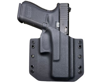 Puede incluir: Una pistola negra está enfundada en una funda de polímero negro. La funda tiene múltiples orificios para tornillos para el montaje. La pistola es una pistola semiautomática con empuñadura texturizada.