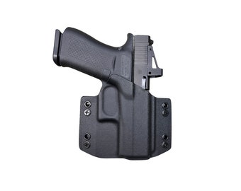 Puede incluir: Una funda de polímero negra con una pistola negra en su interior. La funda tiene varios agujeros para tornillos y está diseñada para llevar oculta.