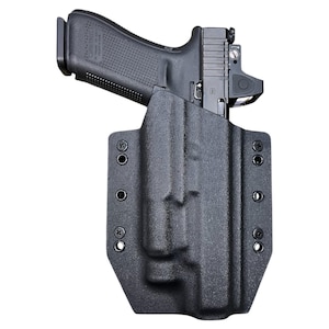 May include: Black handgun in a black holster. The firearm has a red dot sight and is secured in a molded holster with multiple screw holes. The holster is designed for secure carry and easy access.