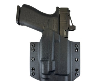 Puede incluir: Funda de polímero negra con una pistola negra en su interior. La funda tiene múltiples puntos de fijación y está diseñada para llevar oculta.