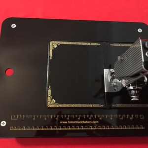 May include: Black sewing machine table with a ruler and the text "www.tailormadetables.com".