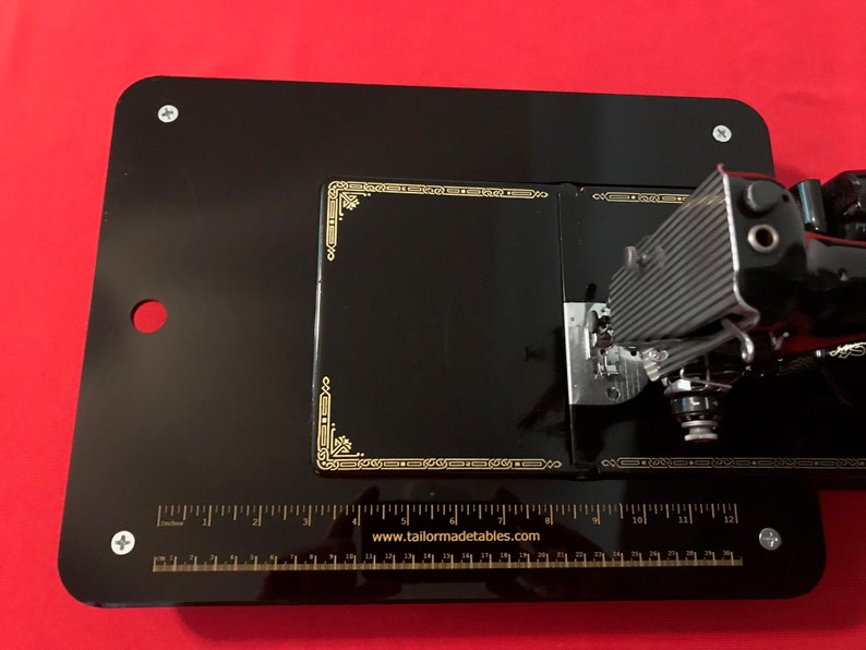 May include: Black sewing machine table with a ruler and the text "www.tailormadetables.com".