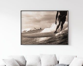 Puede incluir: Una fotografía en blanco y negro de un surfista montando una ola. El surfista está en primer plano y la ola rompe detrás de él. La foto está tomada desde un ángulo bajo, lo que da al espectador una sensación de la velocidad y la potencia del surfista.