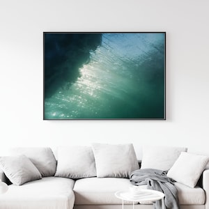 May include: A photograph of a wave breaking, showing the underside of the wave with sunlight shining through the water. The water is a deep green color with white highlights.