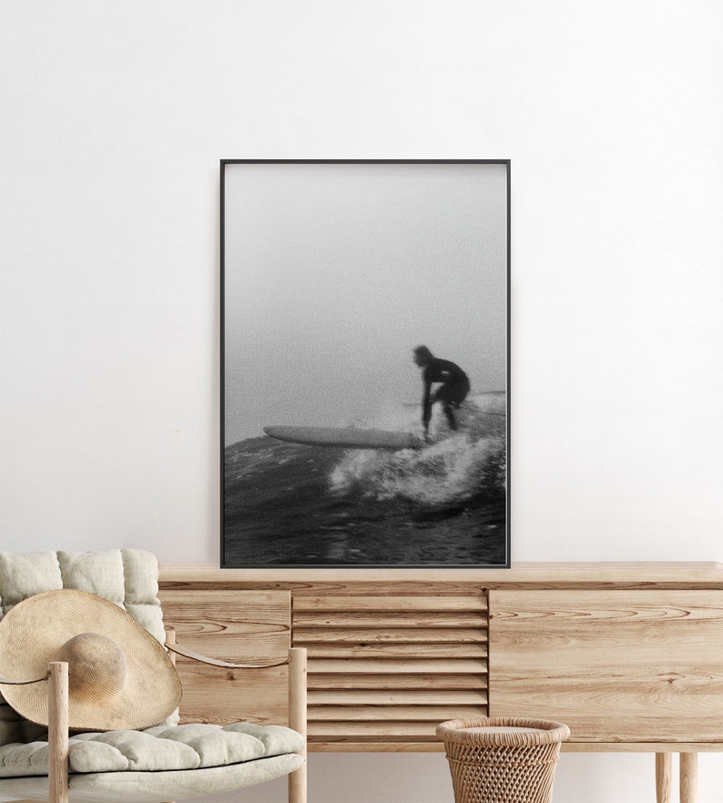 K&ouml;nnte beinhalten: Schwarzwei&szlig;foto von einem Surfer, der auf einer Welle reitet. Der Surfer tr&auml;gt einen Neoprenanzug und ist vor dem Himmel silhouettiert. Die Welle bricht und es gibt viel Gischt.