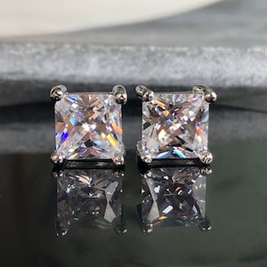 Op de afbeelding: Een paar zilveren vierkante oorbel studs met heldere zirkonia stenen.