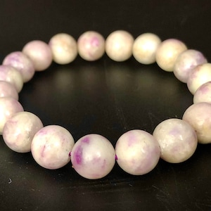 May include: A white and purple gemstone bracelet with round beads. The bracelet is made of natural stones and has a simple design.