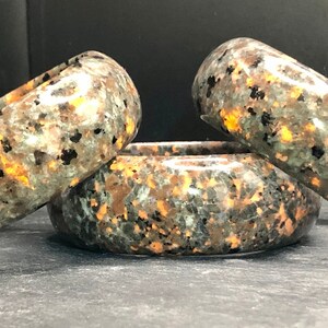 May include: Three polished stone bracelets with a mottled green, black, and copper color pattern.