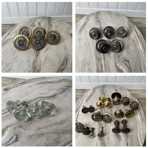 May include: A collection of various cabinet knobs in different styles and finishes. The knobs include brass, bronze, and clear glass options. Some knobs have intricate decorative details, while others are simple and functional.