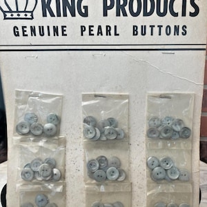 May include: Vintage card of King Products genuine pearl buttons. The card features six small plastic bags, each containing a collection of round, light-colored buttons. The text "KING PRODUCTS GENUINE PEARL BUTTONS" is printed in black on the top of the card.