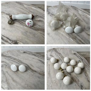 May include: A collection of vintage cabinet hardware, including white porcelain knobs and pulls. The knobs have gold-toned bases, and some are still in their original packaging. One pull has a white porcelain handle and a decorative end.