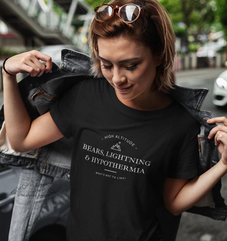 May include: A black t-shirt with white text that reads "High Altitude - Bears, Lightning & Hypothermia - What's not to like?" The text is surrounded by a circle with a mountain peak inside.