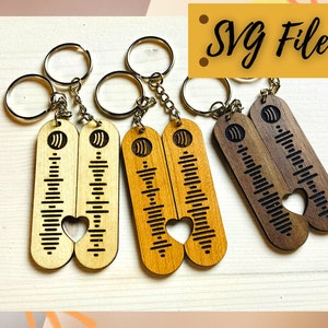 May include: Three sets of wooden keyrings with a heart-shaped cutout. Each keyring features a unique wood grain pattern and a sound wave design. The keyrings are attached to silver key rings.