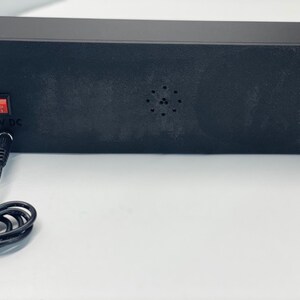 Puede incluir: Un dispositivo electr&oacute;nico rectangular negro con un interruptor de encendido rojo y una entrada de 12V CC. El dispositivo tiene una serie de peque&ntilde;os agujeros y un cable de alimentaci&oacute;n.